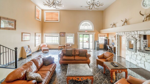 A spacious lobby with leather sofas, a marble coffee table, chandeliers, and a stone fireplace. - Days Inn & Suites by Wyndham Beeville (Beeville)