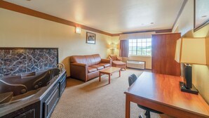 A hotel room with a large bathtub, a sofa, a coffee table, a TV, and a dining table. - Days Inn & Suites by Wyndham Beeville (Beeville)