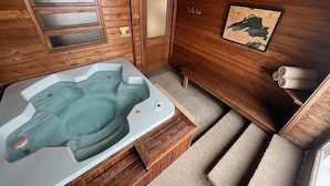 En træhytte med jacuzzi, træbænke, et kort på væggen og et håndklædetørrestativ.