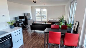 Een moderne keuken met een eethoek, houten vloer en rode stoelen.