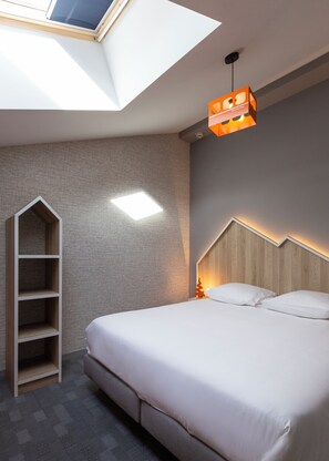A modern bedroom with a skylight, a built-in bookshelf, a wooden headboard, and a bedside table with a lamp. - Base Camp Lodge (Bourg-Saint-Maurice)
