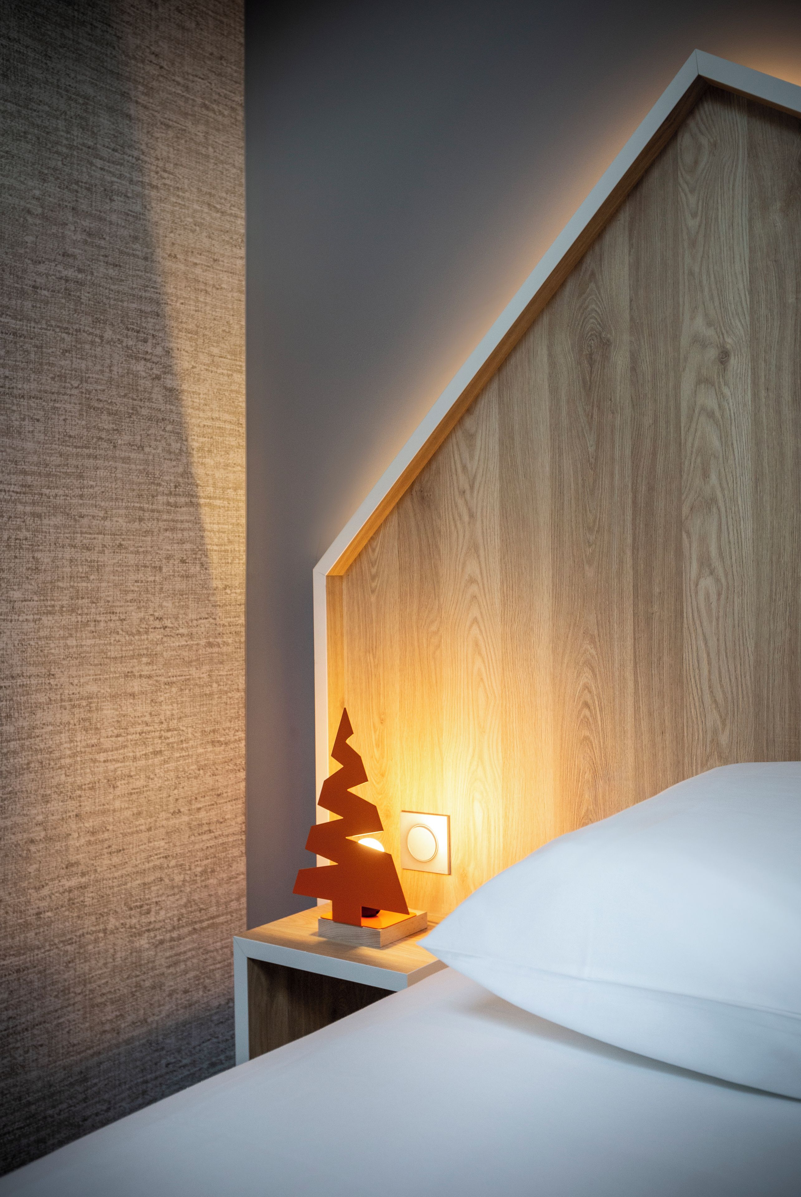 Una cama bien hecha con un almohadón blanco y cabecera de madera.