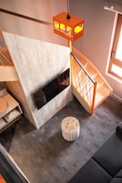A modern interior with a staircase, a fireplace, and a round ottoman.
