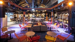 An indoor dining area with multiple tables and chairs, a bar area, and a high ceiling with exposed beams. - Base Camp Lodge (Bourg-Saint-Maurice)