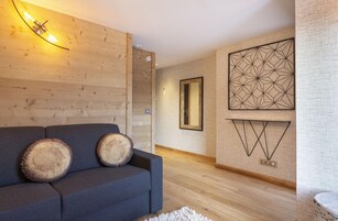 Un salon moderne avec un canapé gris, un lambris en bois et des œuvres d’art murales aux motifs géométriques.