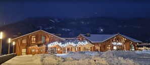 A wooden lodge with a sign reading 'HOTEL BASE CAMP LODGE' and a restaurant sign. - Base Camp Lodge (Bourg-Saint-Maurice)