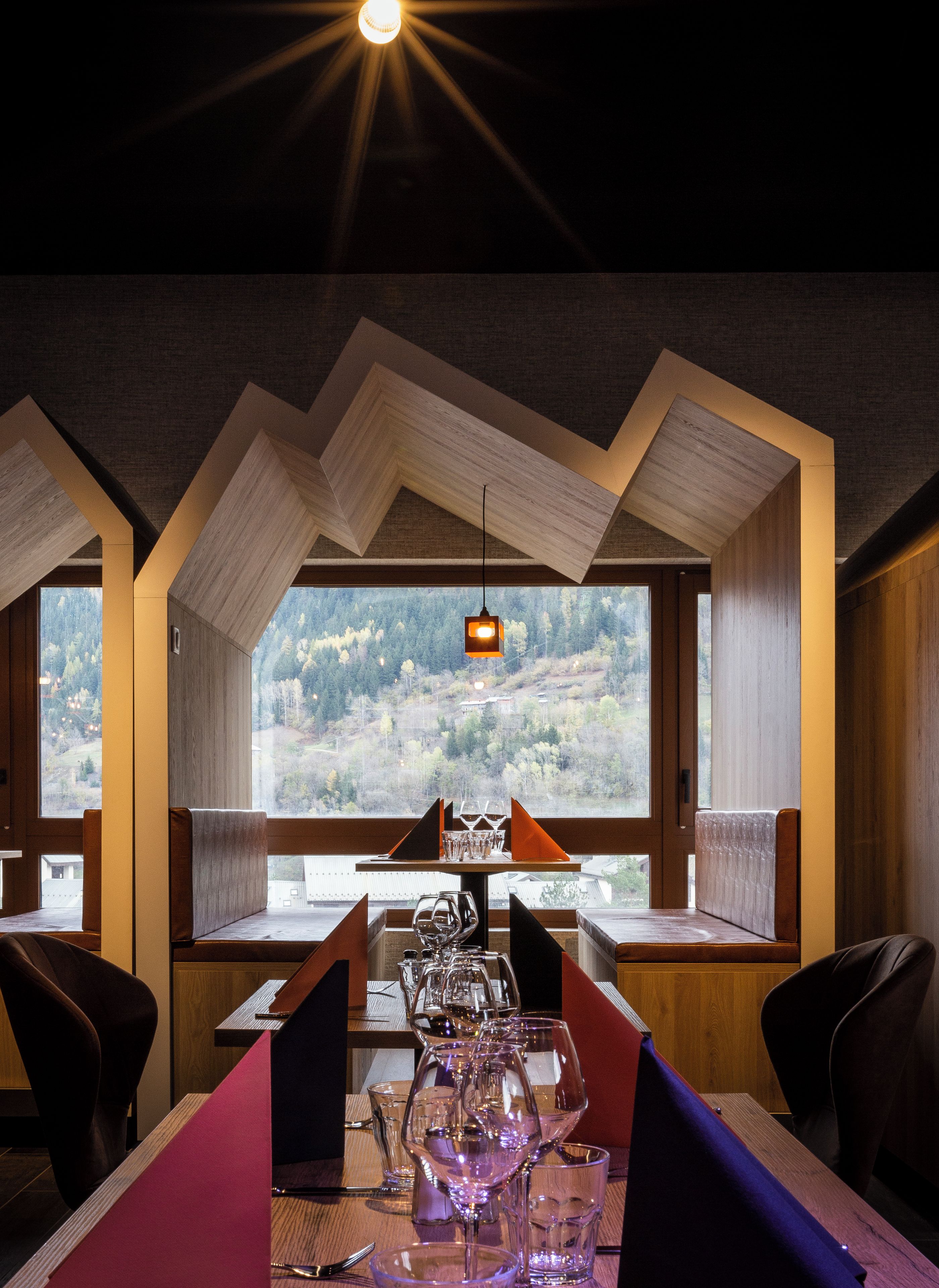 Un restaurante con una mesa lista para comer, vistas al exterior y un diseño de techo singular.
