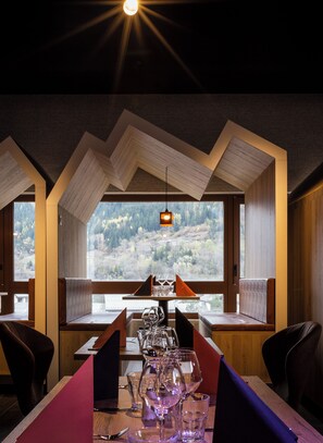 Een restaurant met een gedekte tafel, uitzicht op het omliggende landschap en een bijzonder plafond.