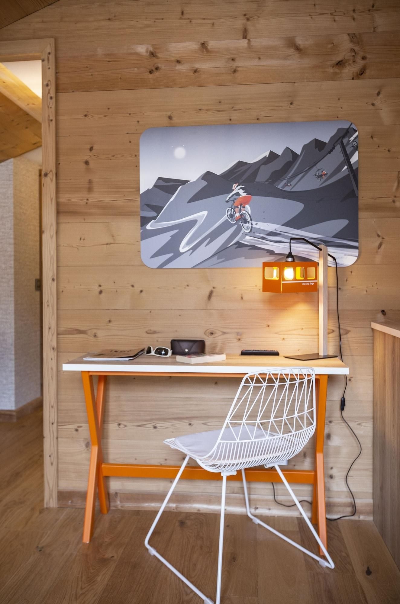 A wooden interior with a desk, chair, and a wall-mounted lamp.