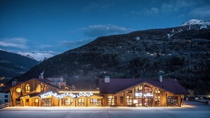 A wooden lodge with a large sign reading 'Hotel Basecamp Lodge' and 'BC7 Restaurant' against a mountainous backdrop. - Base Camp Lodge (Bourg-Saint-Maurice)