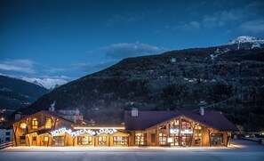 A wooden lodge with a large sign reading 'Hotel Basecamp Lodge' and 'BC7 Restaurant' against a mountainous backdrop. - Base Camp Lodge (Bourg-Saint-Maurice)