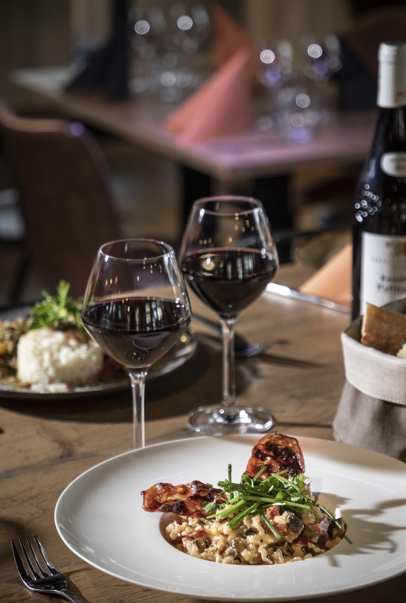 Un tavolo da pranzo con due bicchieri da vino, una bottiglia e un piatto di cibo.
