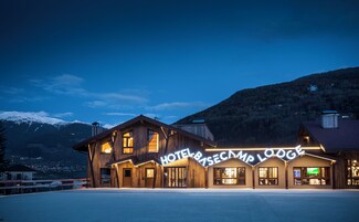 A wooden hotel with a sign reading 'HOTEL & RESCUE CAMP LODGE' against a mountainous backdrop.