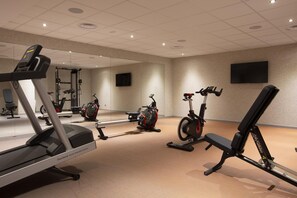 Ett gym med konditionsmaskiner, en motionscykel och en bänk.