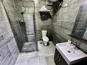 A modern bathroom with a glass-enclosed shower, a white toilet, and a sink with a mirror. - Hurghada - Apartment - Sleeps 6 - Pool - Parking (Hurghada)