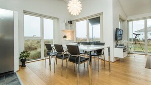 A modern dining area with a white table and chairs, large windows, and a ceiling light fixture. - Lovely home in Thisted with kitchen (Thisted)