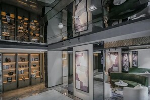 A modern interior with a mezzanine level, open shelving with items, and abstract art. - Joy Hotel Hangzhou (Hangzhou)