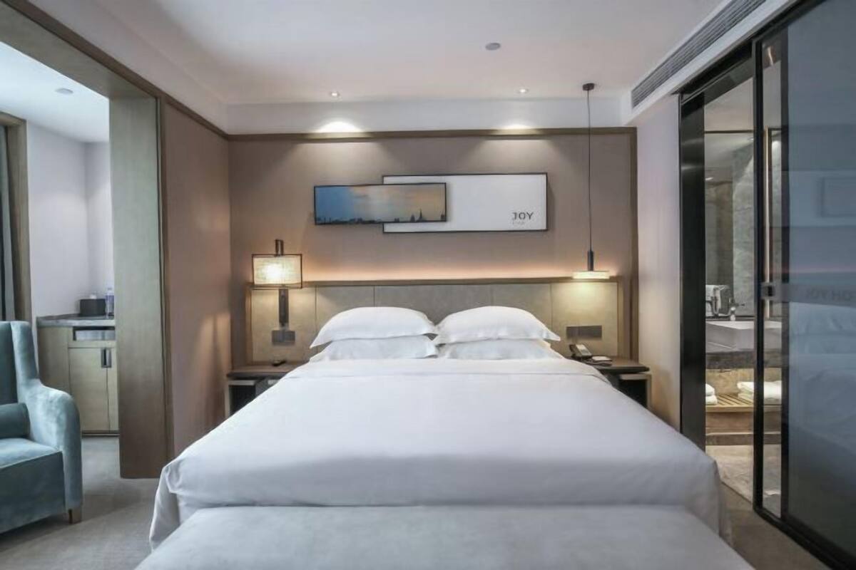 A hotel room with a bed, bedside tables, a lamp, a chair, and a painting on the wall.