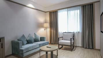 Ein Hotelzimmer mit einer Couch, einem Sessel, einem runden Couchtisch und einem Fernseher.