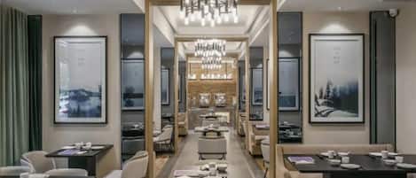A modern hotel lobby with a central walkway, seating areas, and framed artwork on the walls.
