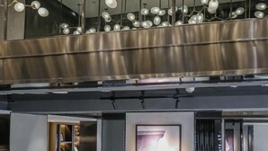Un interior moderno con una escalera metálica, lámparas de diseño contemporáneo y una obra enmarcada en la pared.