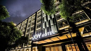 Un hotel con fachada moderna, señalización iluminada y un diseño de ventanas estructurado.