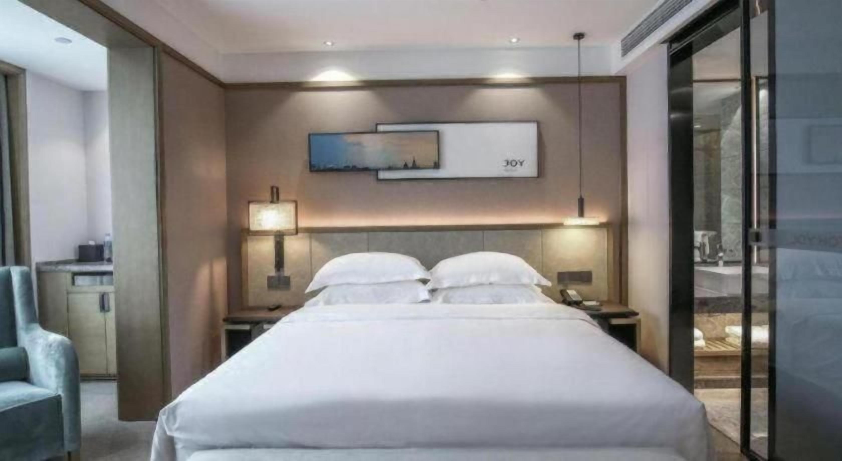 A hotel room with a large bed, bedside tables, a desk, and a chair.