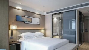 A modern hotel room with a large bed, bedside tables, a wall-mounted lamp, and a sliding glass door to a bathroom. - Joy Hotel Hangzhou (Hangzhou)