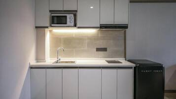 Una cocina moderna con armarios blancos, un microondas integrado y un electrodoméstico negro identificado como 'HUBKY IOBAR'.