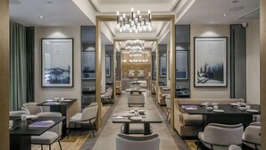 Un moderno vestíbulo de hotel con un área de estar central, obras de arte enmarcadas en las paredes y un candelabro.