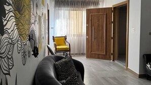 Un salon avec un canapé, un fauteuil jaune et un mur orné d’un motif.