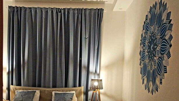 Une chambre à coucher comprenant un lit, une table de chevet, une lampe et un élément décoratif mural.
