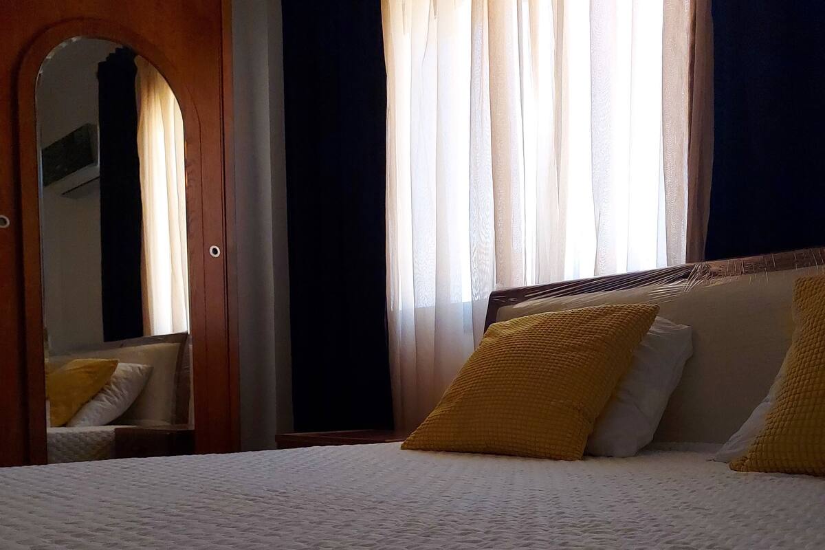 Ein Hotelzimmer mit einem großen Bett, einer Holztür und einem Spiegel.