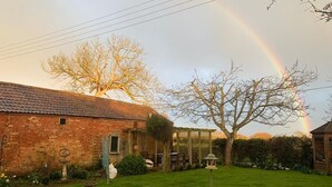 A brick house with a garden, a tree, and a rainbow. - River and country views & woodburner at ‘The Nest’ (Burrowbridge)