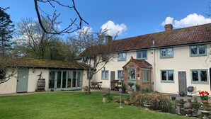 A traditional two-story house with a well-maintained lawn and garden. - River and country views & woodburner at ‘The Nest’ (Burrowbridge)