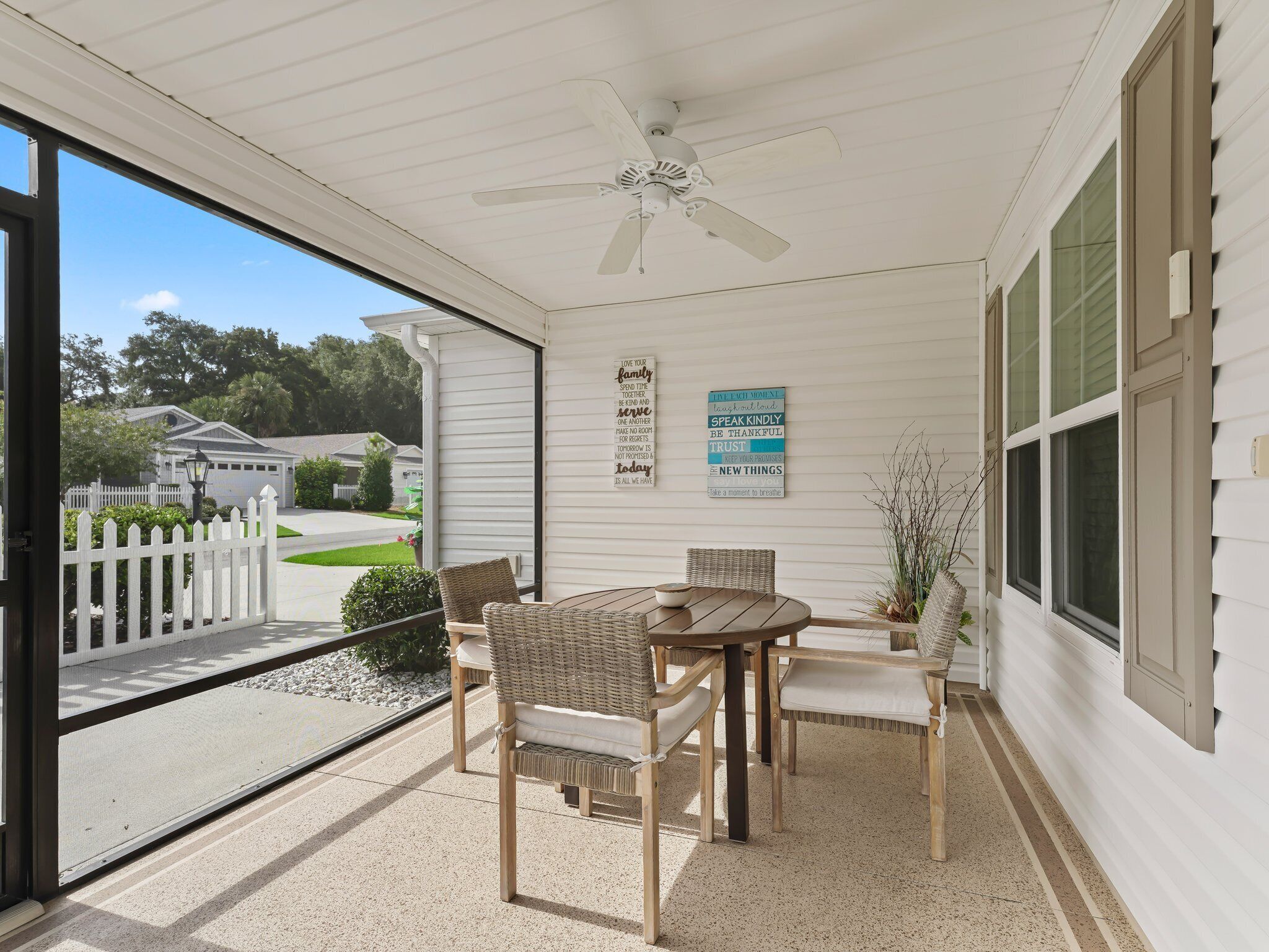 A covered porch with wicker furniture, a ceiling fan, and a view of a residential street.