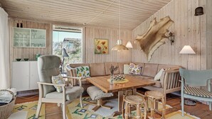 Una habitación acogedora con techo de madera, un alfombra de piel grande, una mesa de comedor de madera y un sofá.