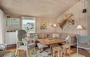Cozy space with a rustic aesthetic, featuring a sofa, chairs, dining table, and a large wall-mounted fur piece.