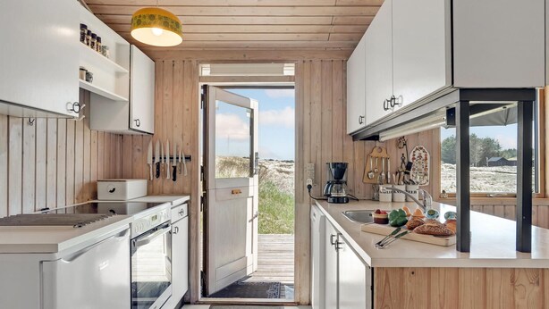 Una cocina moderna con armarios de madera, horno empotrado y cafetera.