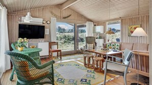 Interior acogedor de una cabaña con paredes de madera, un comedor, una sala de estar y un ventanal con vistas al exterior.