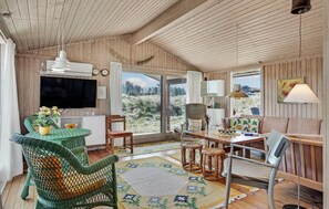 Relax in a spacious room with a high ceiling, comfortable seating area, and large windows offering a view of the surrounding landscape.