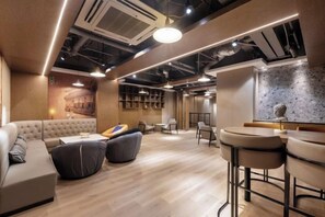 A modern lounge area with a sofa, round tables, and a bar. - Rely Hotel Flagship (Nanshan Hi-tech Park, Shenzhen) (Shenzhen)