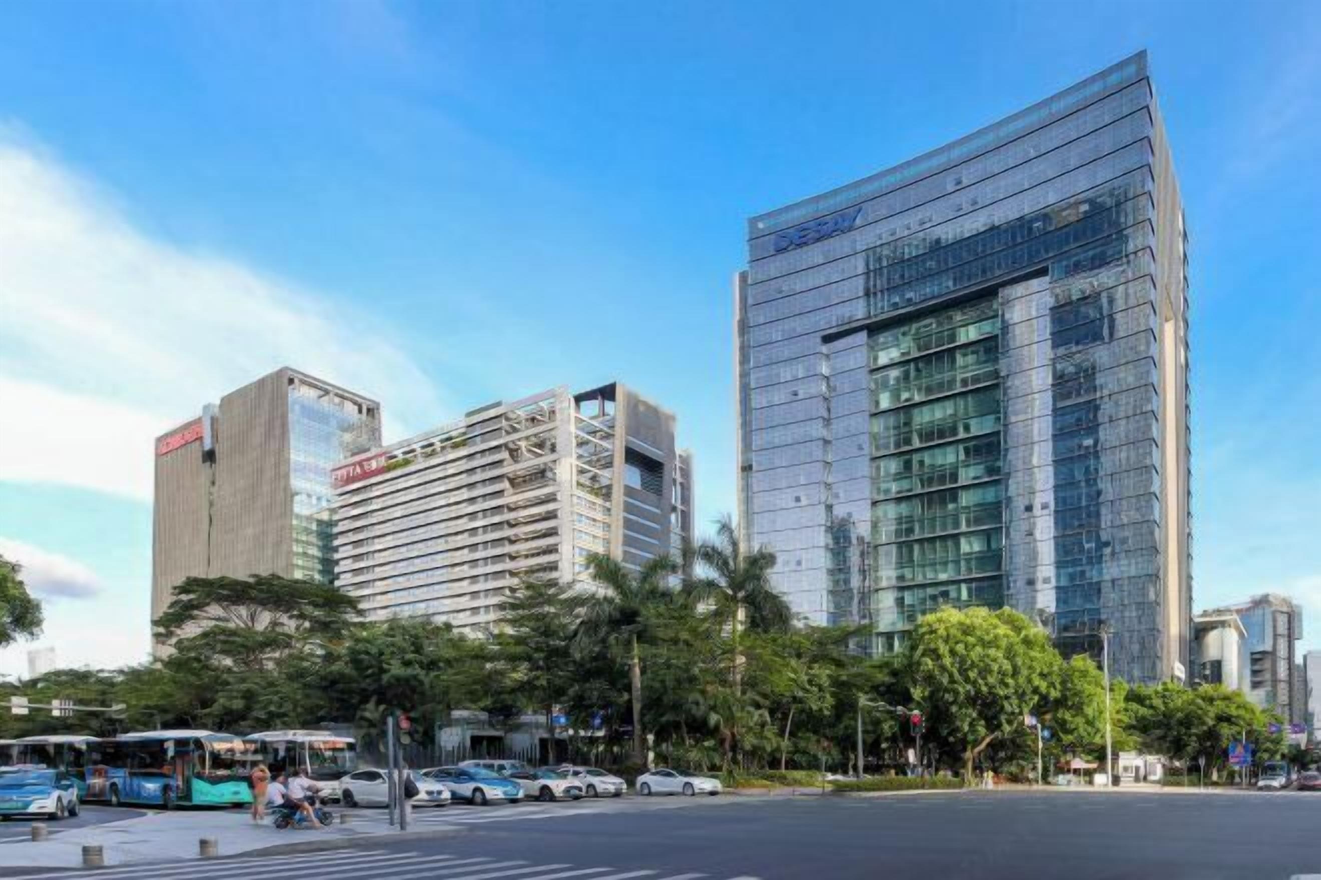 A modern urban street with high-rise buildings, including a prominent glass skyscraper.