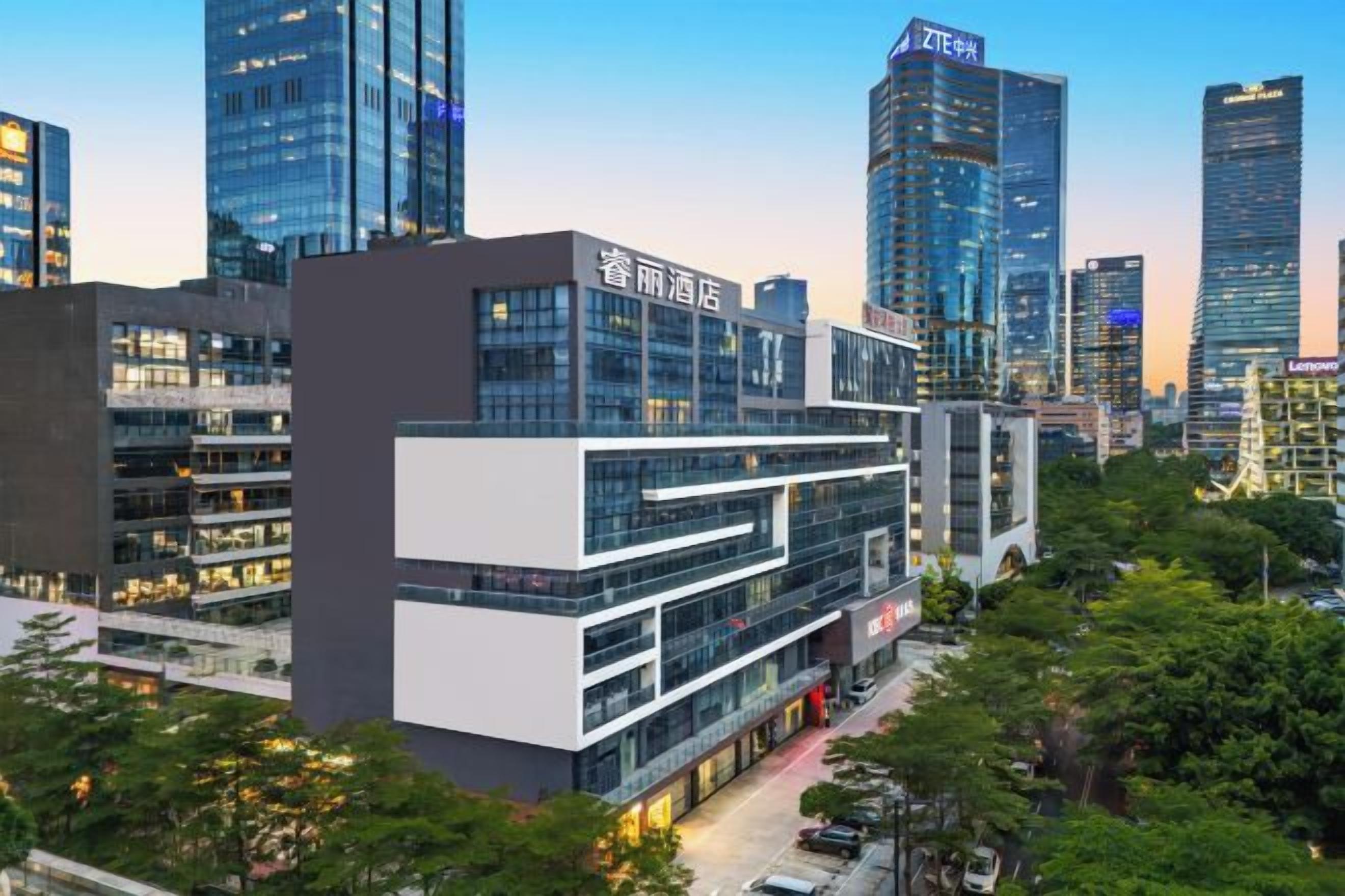 A modern hotel with multiple floors, large windows, and a prominent entrance.