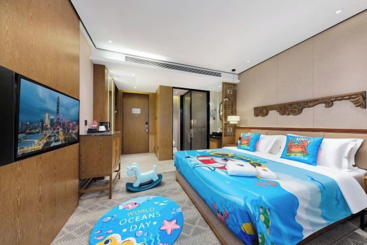 Habitació d'hotel amb llit, escriptori, televisió i vista a la ciutat.