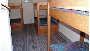Ein Zimmer mit Etagenbetten, einem kleinen Schrank und einem gerahmten Bild an der Wand.