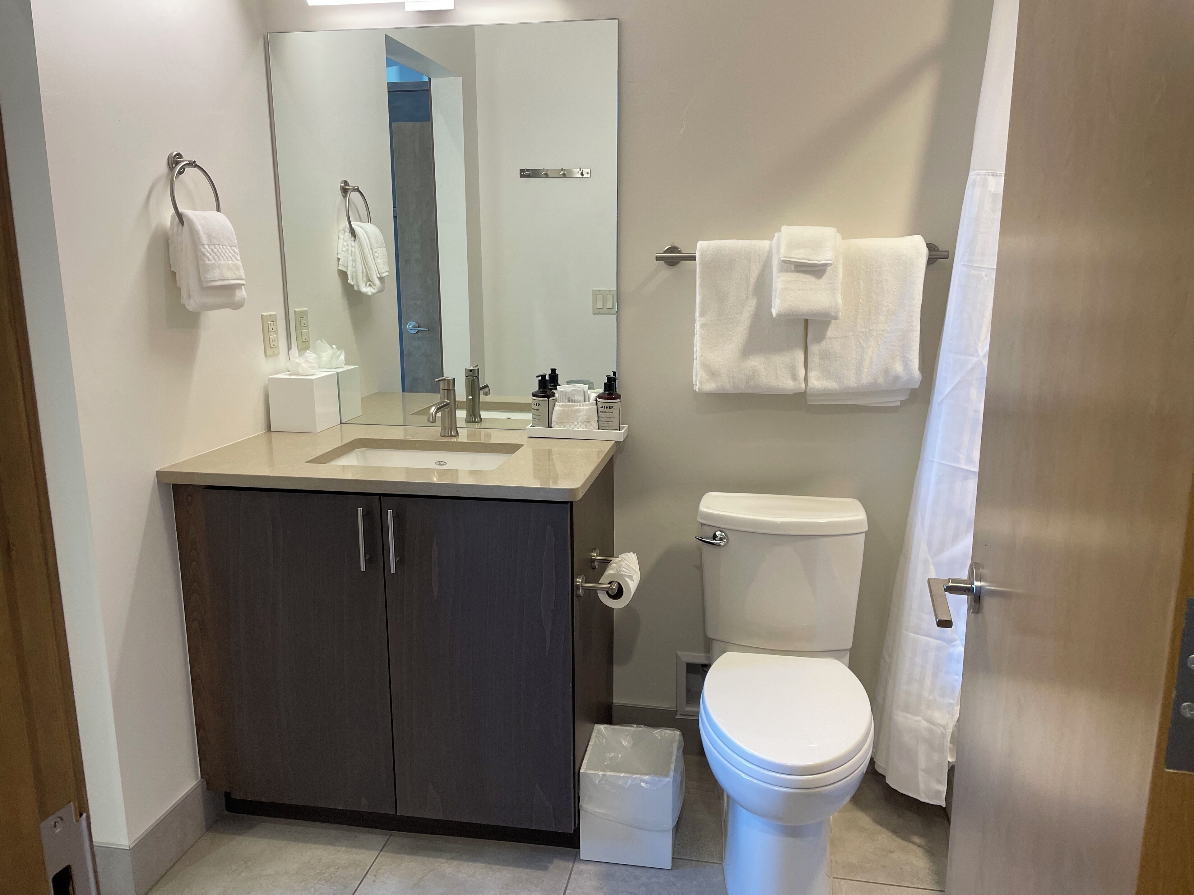 Une salle de bain moderne équipée d’un lavabo, d’un miroir, de toilettes et d’un porte-serviettes.