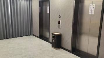 An elevator area with metallic walls, a tiled floor, and two elevators.