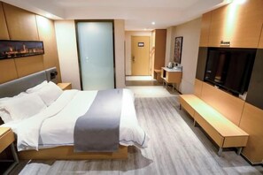 Una habitación de hotel con una cama, mesitas de noche, un banco, un televisor y un escritorio.