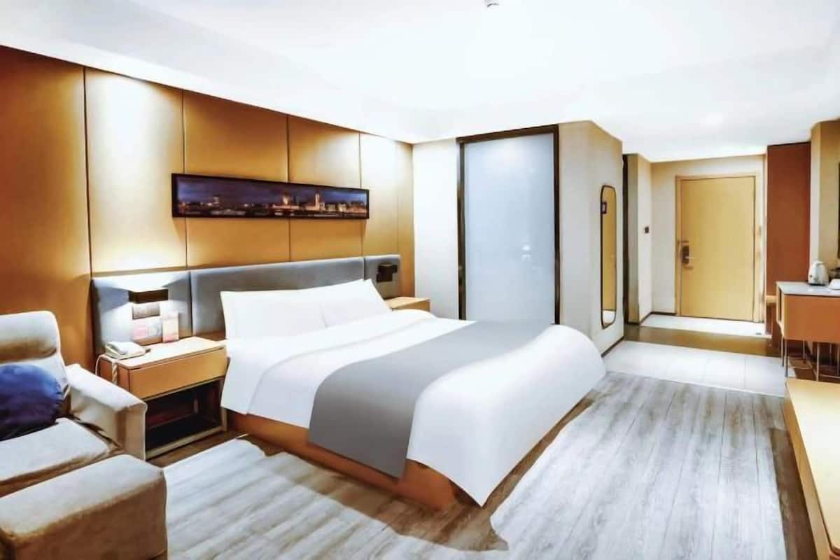 A modern hotel room with a large bed, a desk, and a seating area.